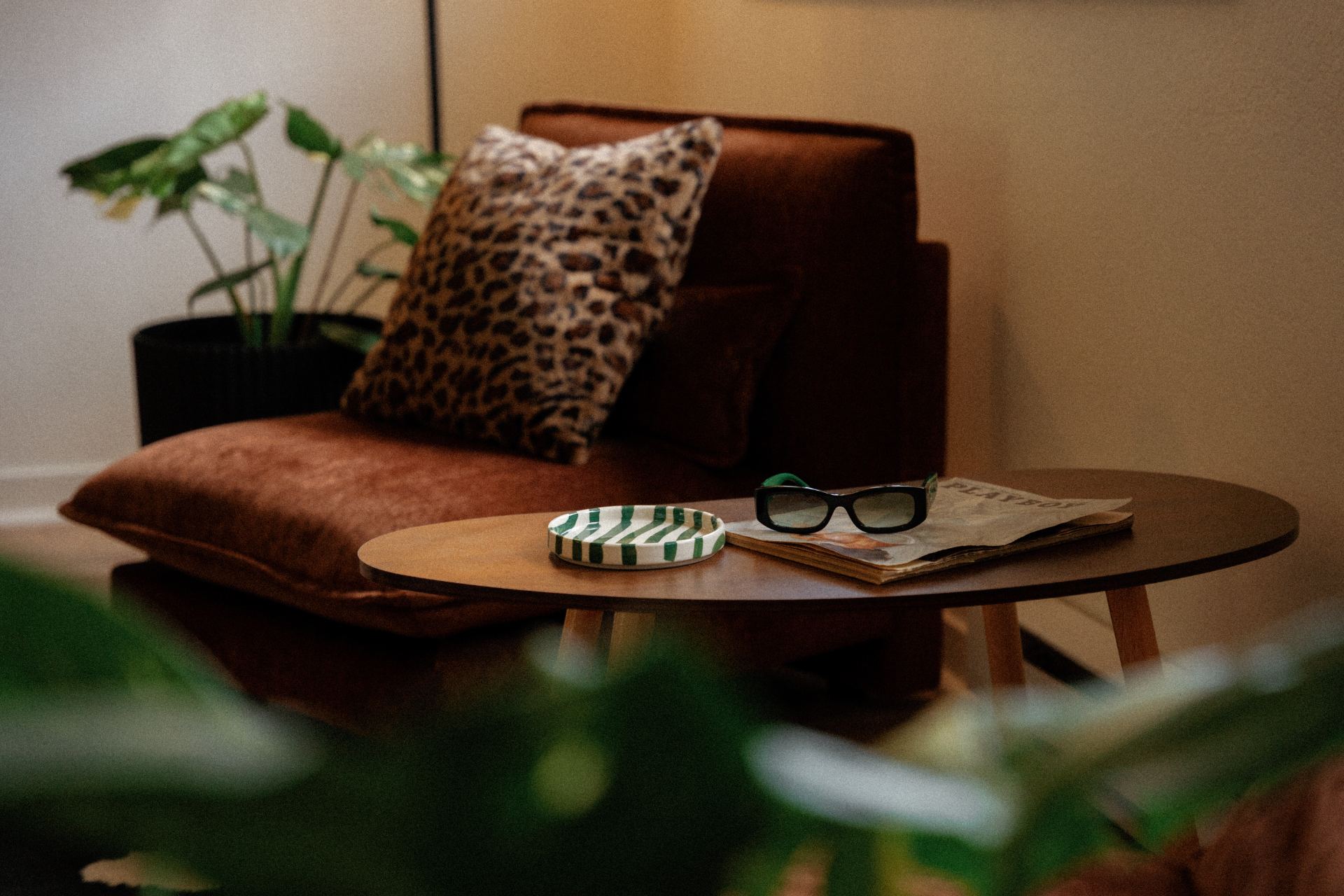 Velvet armchair with leopard pillow and styled coffee table in the studio