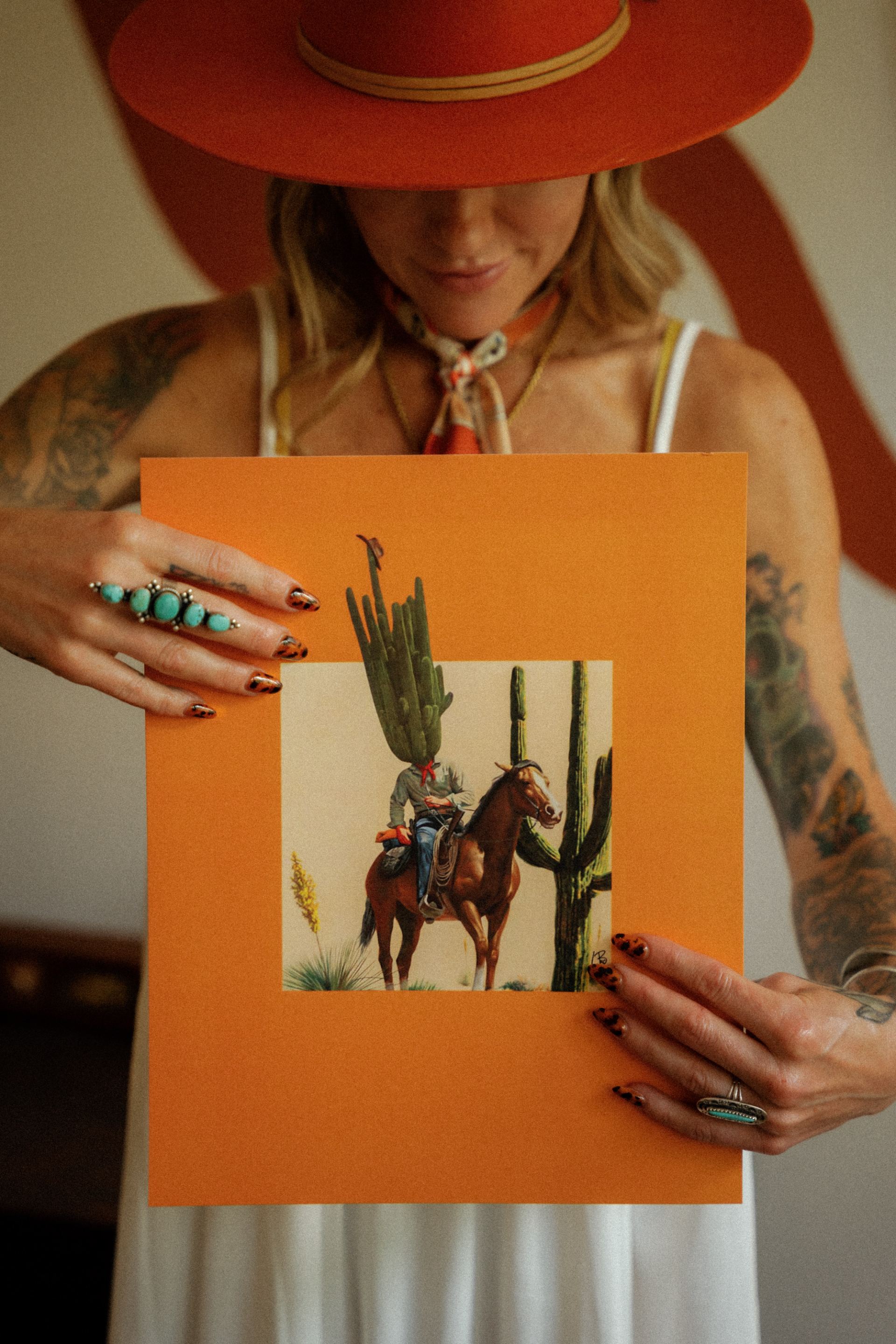 Tortoiseshell nails holding a cactus-and-cowboy art print