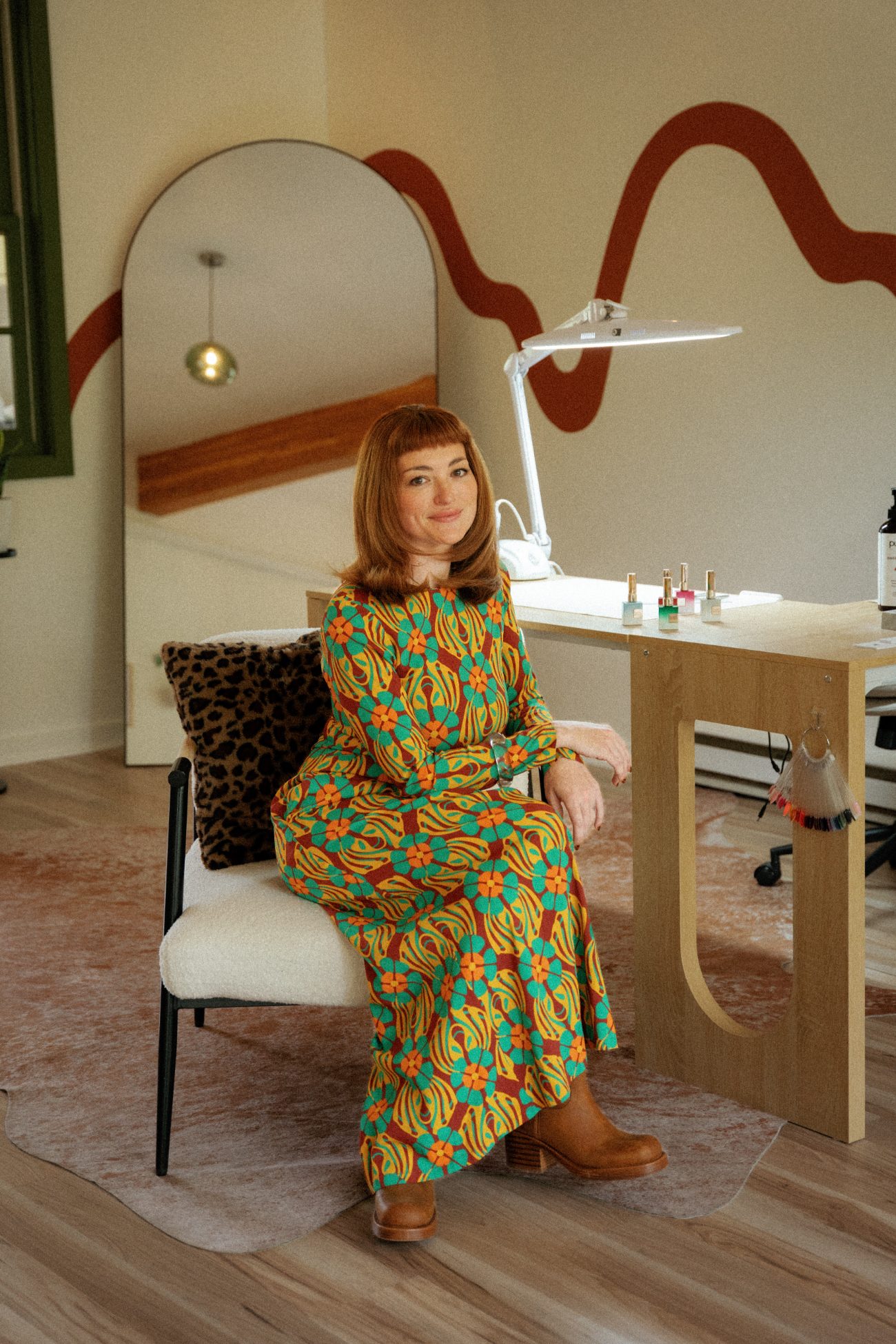 Kira seated at her manicure desk in the Basalt studio, polish bottles lined up beside her